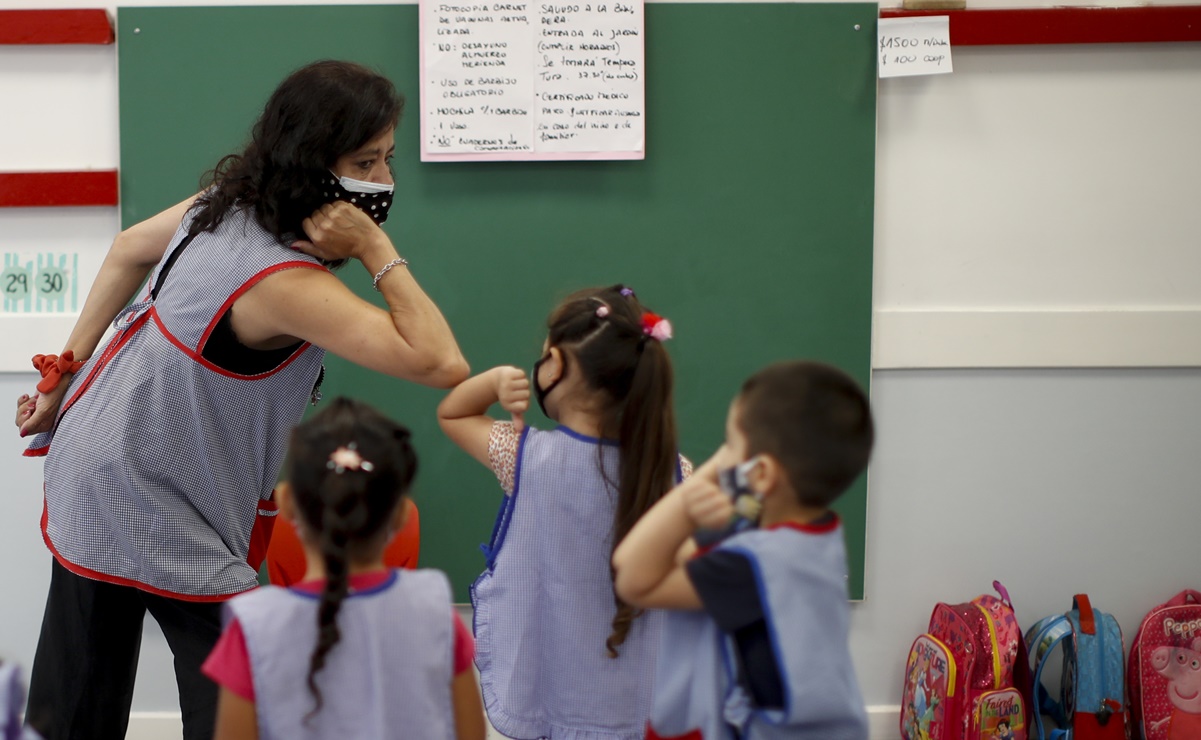 Raquel Echeverria teaches her 5-year-old students to greet each other with an elbow bump on the first day back to class amid the COVID-19 pandemic in Buenos Aires, Argentina, Wednesday, Feb. 17, 2021. The capital city is returning its public school students to in-person classes on Wednesday with alternating attendance. (AP Photo/Natacha Pisarenko)